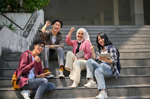 A group of Asian-diverse college students rejoicing and celebrating their school success stock photo