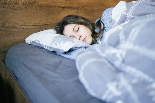 Young teenager girl sleeping snuggled in warm duvet