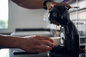 Close-up of man making coffee at home.