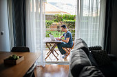 Man working on laptop and relaxing on balcony.