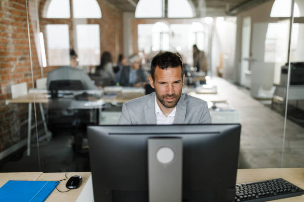 istock Mid adult entrepreneur working desktop PC in the office. 1477724955