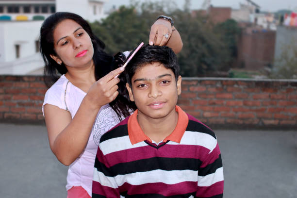 Elder sister combing for her cute small brother at home.