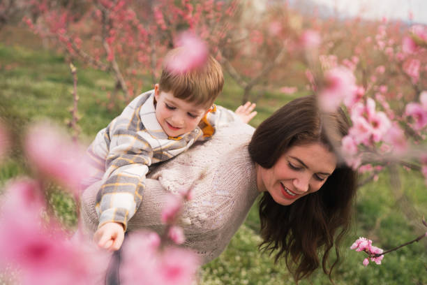 istock Mother carrying toddler son on a back, while both enjoy the spring day 1477727253