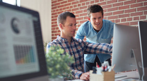 istock Computer, SEO questions or manager helping reading or coaching a worker in startup or group project. Leadership, faq or employee asking, talking or speaking to a man in a digital marketing agency 1477727317