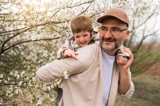 istock Father carrying toddler son on a back, while both enjoy the spring day 1477727454