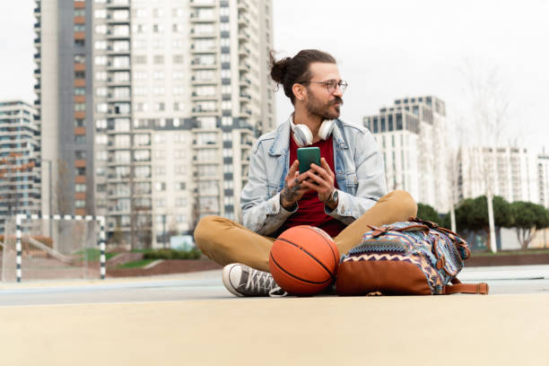 istock Young man enjoying after playing street basket and using smartphone 1477729142