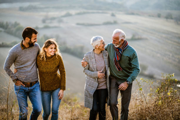 istock Happy couples talking while walking embraced on the field. 1477729317