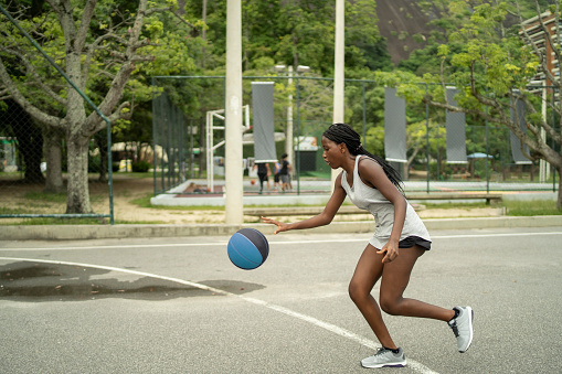 Jugadora brasileña carga por la cancha driblando el balón de baloncesto photo