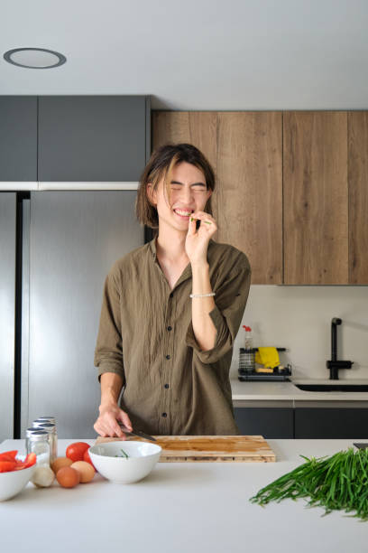 istock Asian young man biting chinese chive at kitchen while cooking. 1477731099