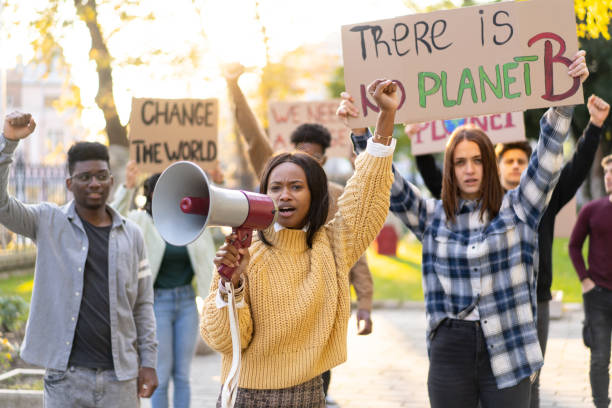 Young protestors rebelling about climate change A group of students using posters and banners and a megaphone are holding an environmental protest for sustainable lifestyles climate justice stock pictures, royalty-free photos & images