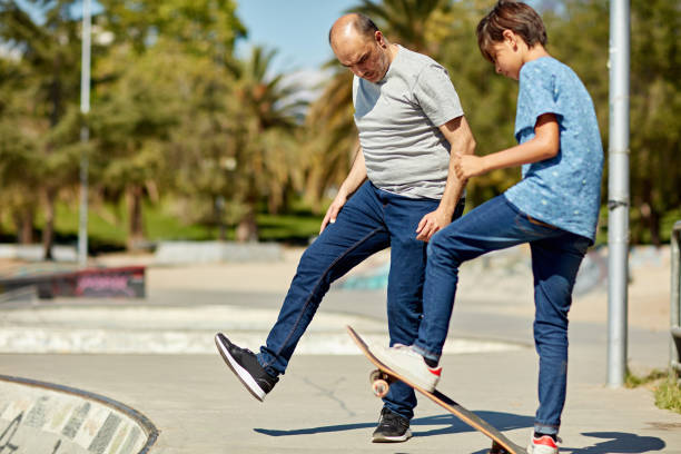 istock Father showing son how to skateboard into bowl 1477731852