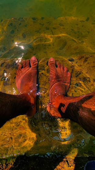 foot dipped in pond clear water