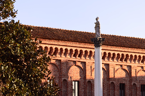 Sabbioneta - Italy. December 12, 2021: The column with the statue of Minerva (Colonna di Minerva) stands on the square in front of the Galleria degli Antichi in Sabbioneta