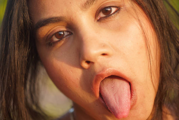 Indian Asian young female close up portrait  of emotion facial gesture of sticking the tongue out in a bored manner stock photo