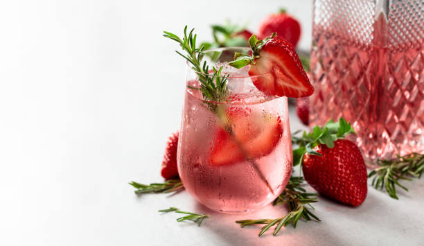 Gin and tonic cocktail with natural ice, strawberries, and rosemary. stock photo