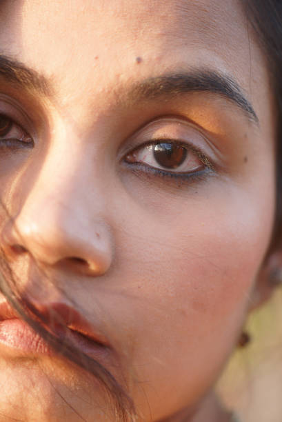 Indian Asian young beautiful female extreme macro close up portrait of eyes and lips emotions sad mood feeling in outdoors daylight with hair covering eyes and face stock photo