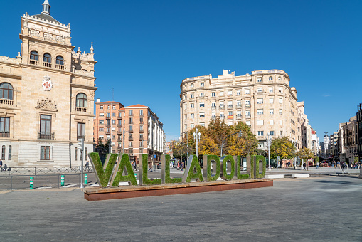 Valladolid, Spain - November 12 2022: Cavalry Academy building in the center of Valladolid, In front is written the name of the city written decorated with grass an flowers. Plaza de Zorrilla Square