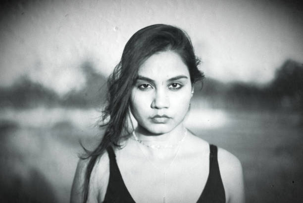 Indian Asian young female close up portrait of neutral emotion facial mood in outdoors black and white image is treated to look like old daguerreotype camera print stock photo
