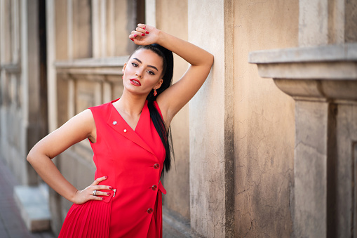 Portrait of charming young Caucasian woman wear red dress at the city