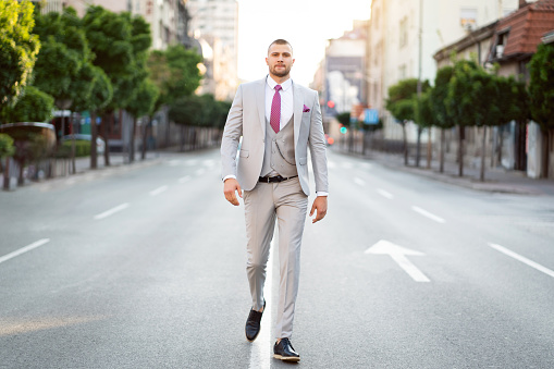 Portrait of a handsome young man in a suit, while walking on the street