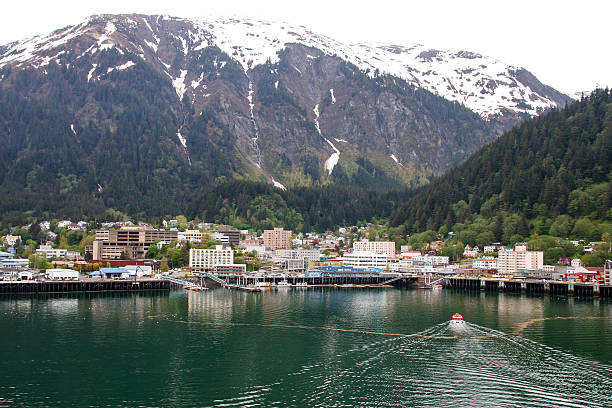 Lifeboat Cruising into Juneau Alaska A ship's tender cruising into the port at Juneau, Alaska with snow covered mountains in background juneau stock pictures, royalty-free photos & images