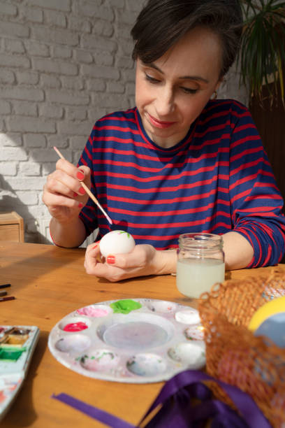 istock Woman painting Easter Egg and preparing for Easter holiday celebration 1477743998