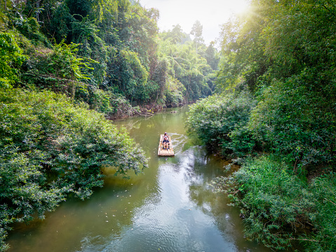 A tourist couple on a bamboo float at a river cruise adventure in the Khao Sok national park, Thailand