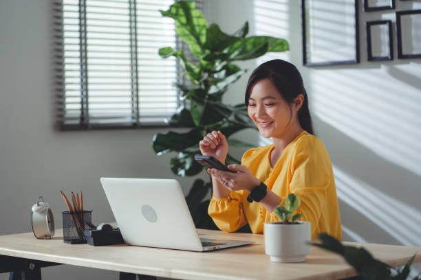 istock Asian woman enjoy with working online and using smartphone sitting at home office. 1477758729