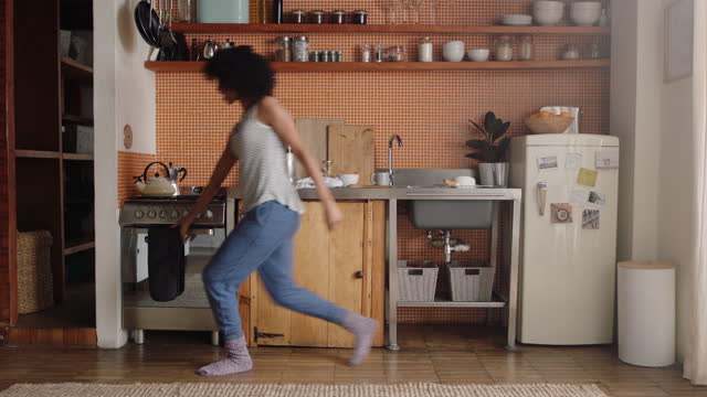 happy woman dancing in kitchen celebrating successful lifestyle enjoying cheerful victory dance celebration