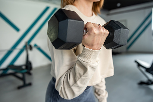 Fitness woman in training with big dumbbells for sports. A close-up display of strong hands. healthy body