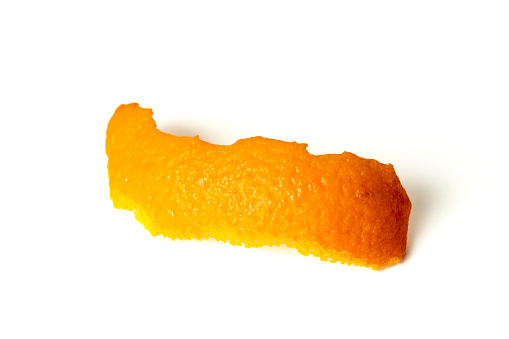 Zest close-up on a white background. The outer side of the orange peel, a ragged uneven edge. isolated