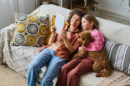 High angle view of family of two spending their free time at home together with dog using digital tablet