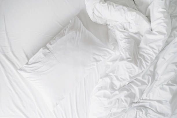 istock white cushion and blanket on wrinkled bed sheet, closeup 1477766528