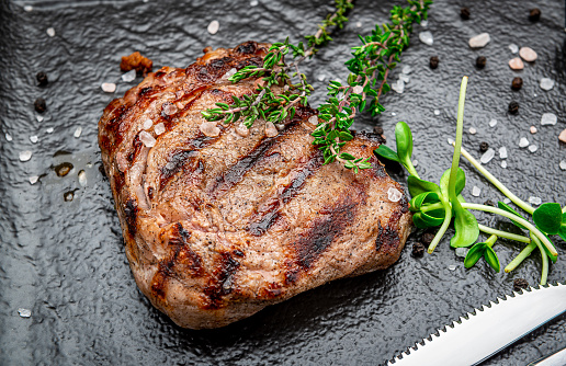 Beef rump steak on black stone table. Photo for the menu