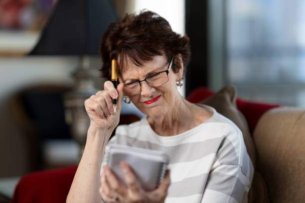 istock Senior woman with pen and notepad at home, looking stressed 1477768882