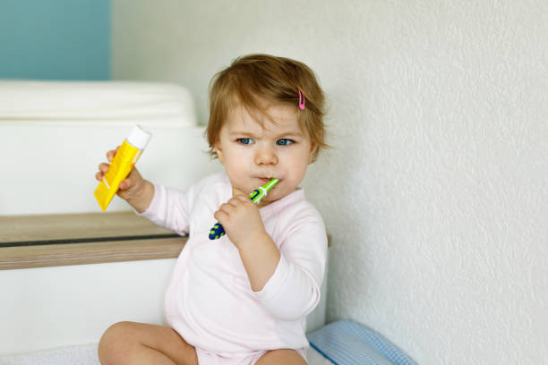 kleine mädchen mit zahnbürste und zähneputzen. kleinkind lernen milchzahn zu reinigen. prävention, hygiene und gesundheitskonzept. glückliches kind im badezimmer - romrodinka stock-fotos und bilder