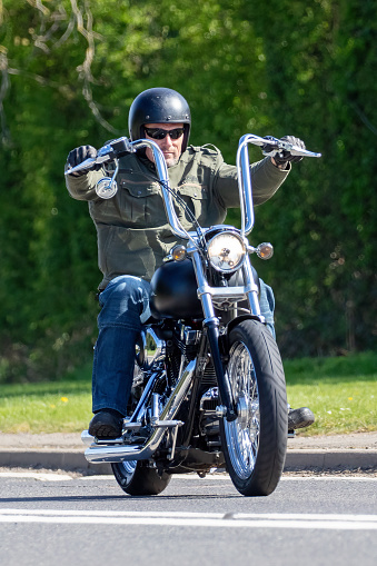 Bicester, Oxfordshire, UK - April 15th 2022. Man riding a Harley Davidson motorcycle on an English country road
