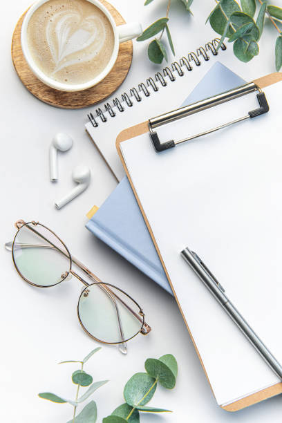 istock Modern white office desk table with coffee, notebook and other supplies. 1477771986