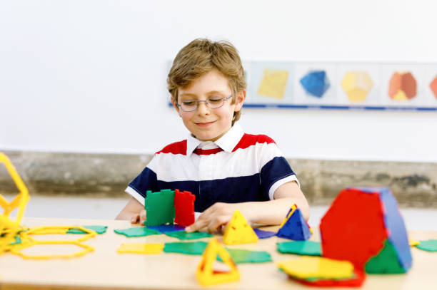 istock Happy kid boy with glasses having fun with building and creating geometric figures, learning mathematics and geometry 1477774923