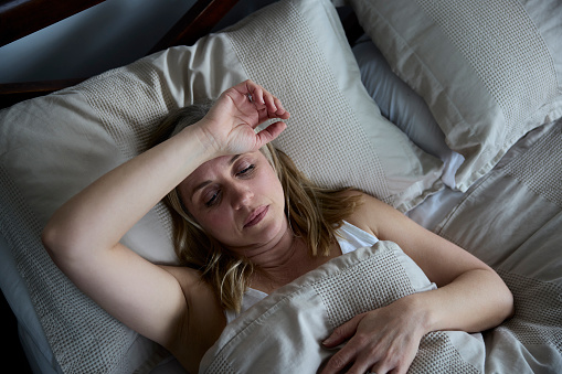 Mujer madura menopáusica que sufre de insomnio en la cama en casa photo
