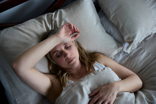 donna matura in menopausa che soffre di insonnia a letto a casa - menopause foto e immagini stock