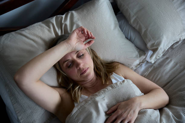 menopauzalna dojrzała kobieta cierpiąca na bezsenność w łóżku w domu - snow house color image horizontal zdjęcia i obrazy z banku zdjęć