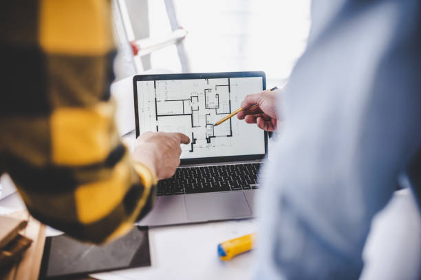 istock Hands of two architects pointing at the architectural plan on the screen 1477776131