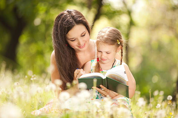 istock Mother and daughter reading in grassy park 147777702