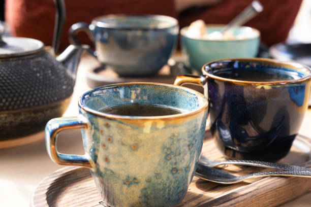 istock Brewing and Serving Tea. Teapot Pouring Green Tea in Blue Ceramic Cup on Wooden Cafe Table. Two Pottery Handmade Mugs Early in the Morning. Trendy Authentic Porcelain Set. Breakfast Concept. Tea Time. 1477778678