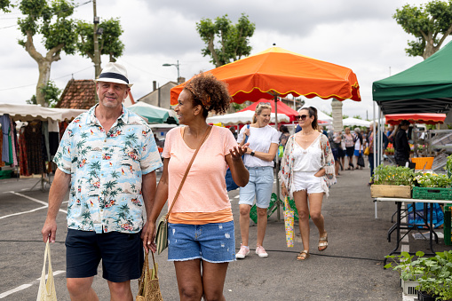 A medium close up of a semi-retired couple who are enjoying getting away from it all and having a carefree relaxing trip to the south of France. They have visited a local fresh produce market.