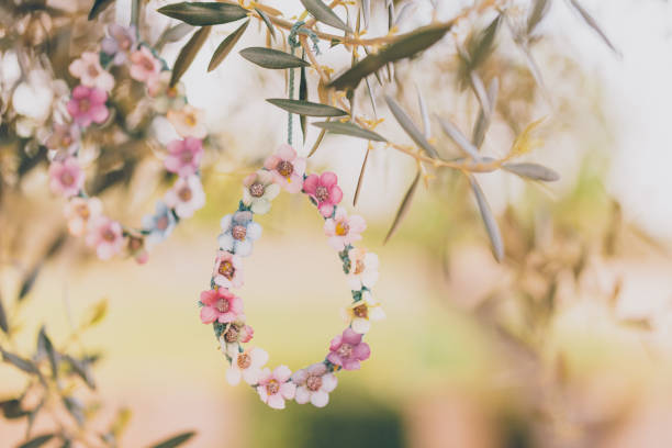 Two diy self made bloomy Easter eggs of macrame and textile flowers hanging on an olive tree. Creative color editing with added grain. Very soft and selective focus. Part of a series.