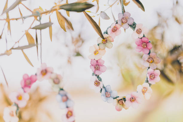Close up of two pastel colored self made bloomy Easter eggs of macrame and textile flowers hanging on an olive tree. Creative color editing with added grain. Very soft and selective focus. Part of a series.