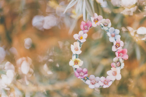 Self made bloomy Easter egg of macrame and textile flowers hanging on an olive tree. Creative color editing with added grain. Very soft and selective focus. Part of a series.