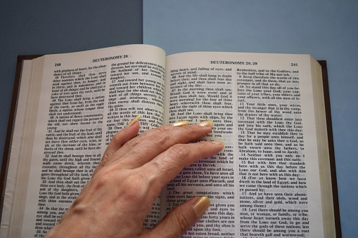 A female hand on the open Bible book.